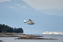 Tofino Air floatplane takes off from Silva Bay with BC ferries ferry behind, Gabriola , British Columbia, Canada Photo: Peter Llewellyn