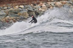 Winter surfers riding waves Cherry Hill, Arties Cove, Nova Scotia, Canada.