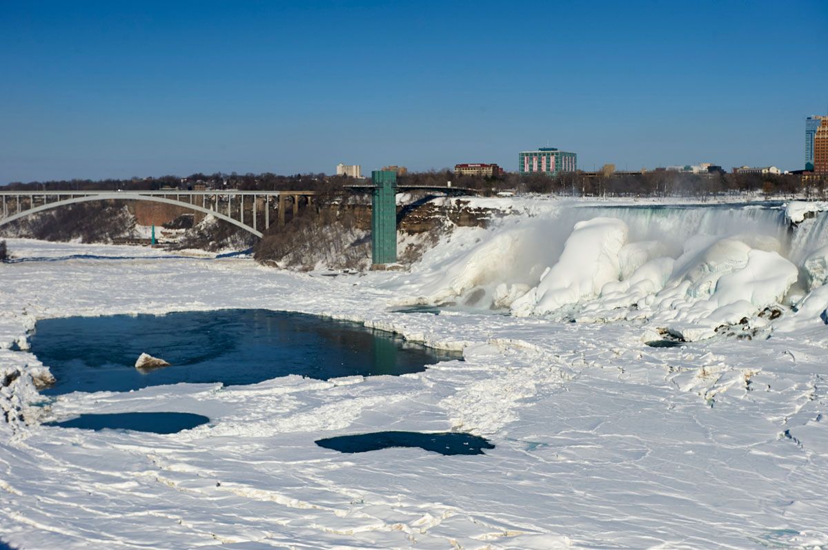 Frozen Niagara falls - the American Falls with Rainbow Bridge in background, from the Canadian side.