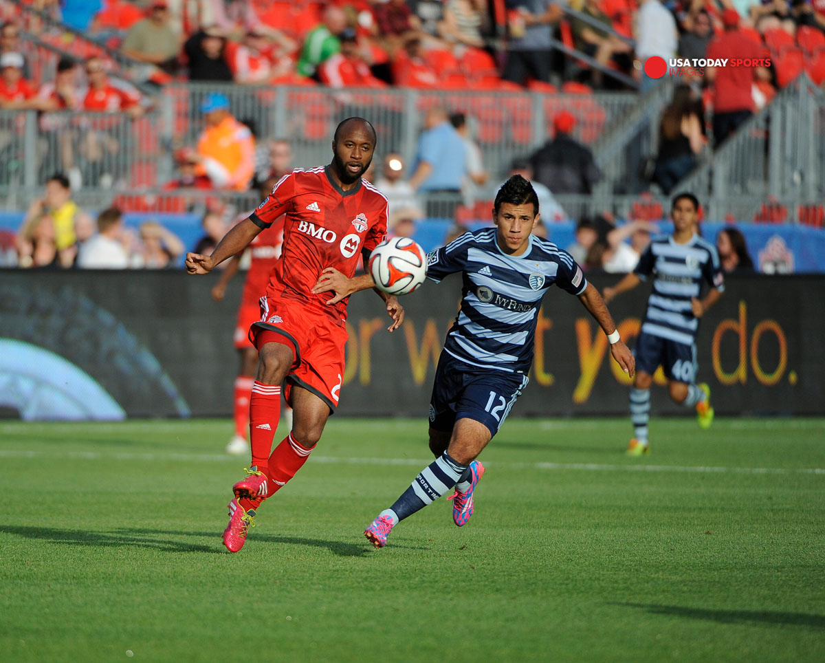 Jul 26, 2014; Toronto, Ontario, CAN; Toronto FC mid-fielder Collen Warner (26) gets past Sporting Kansas mid-fielder Mikey Lopez (12) in first half of game at BMO Field. Mandatory Credit: Peter Llewellyn-USA TODAY Sports