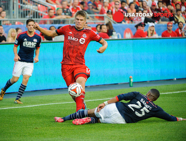 Aug 30, 2014; Toronto, Ontario, CAN; Toronto FC defender Nick Hagglund (17) avoids a sliding tackle from New England Revolution Defender Darrius Barnes (25) at BMO Field. New England won 3-0. Mandatory Credit: Peter Llewellyn-USA TODAY Sports